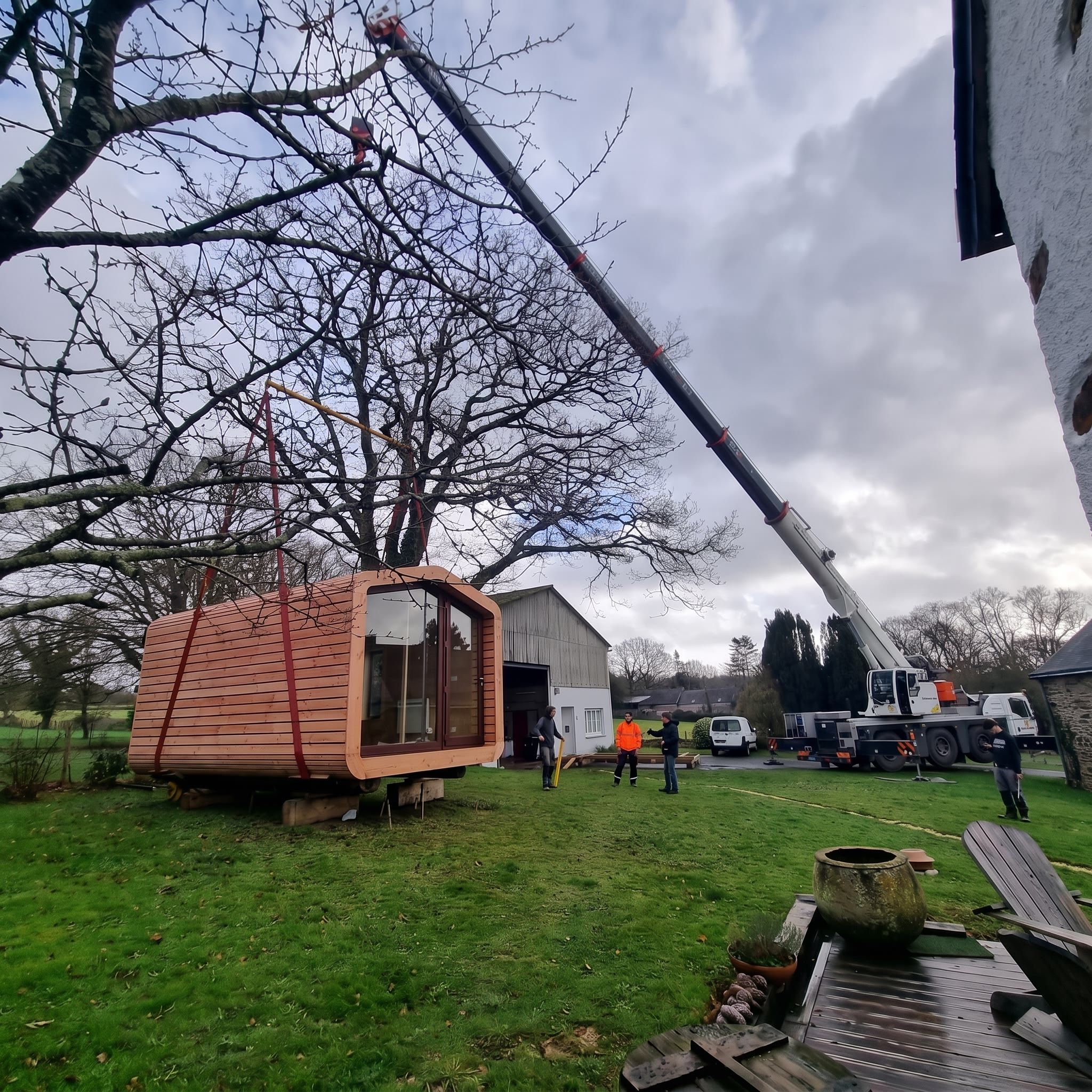 Mise en place d'un module en bois dans un jardin, à la grue mobile