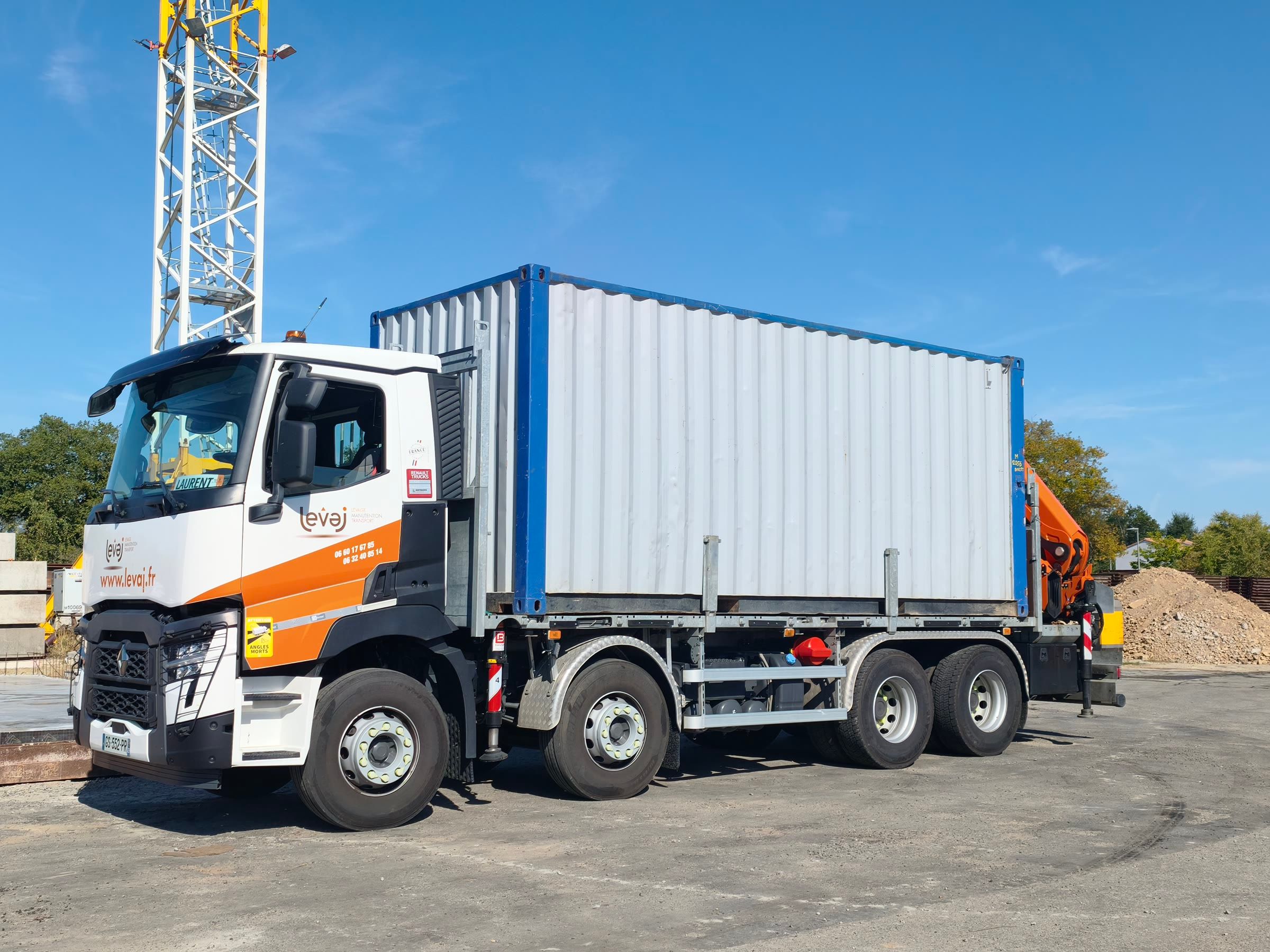 Le porteur Renault de LEVAJ chargé d'un conteneur, sa grue orange repliée à l'arrière