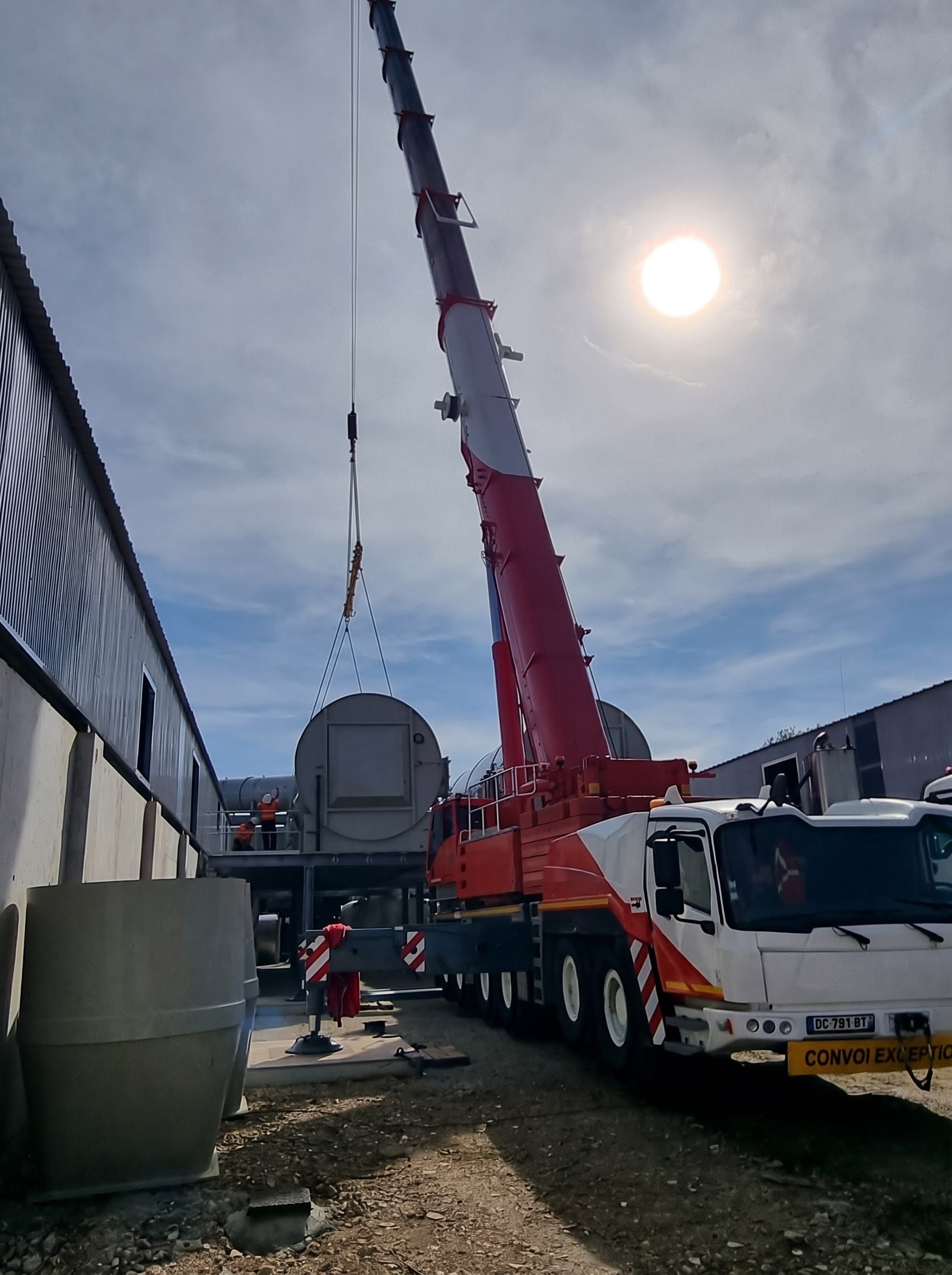 Grue mobile pendant le levage d'une cuve sur un site industriel