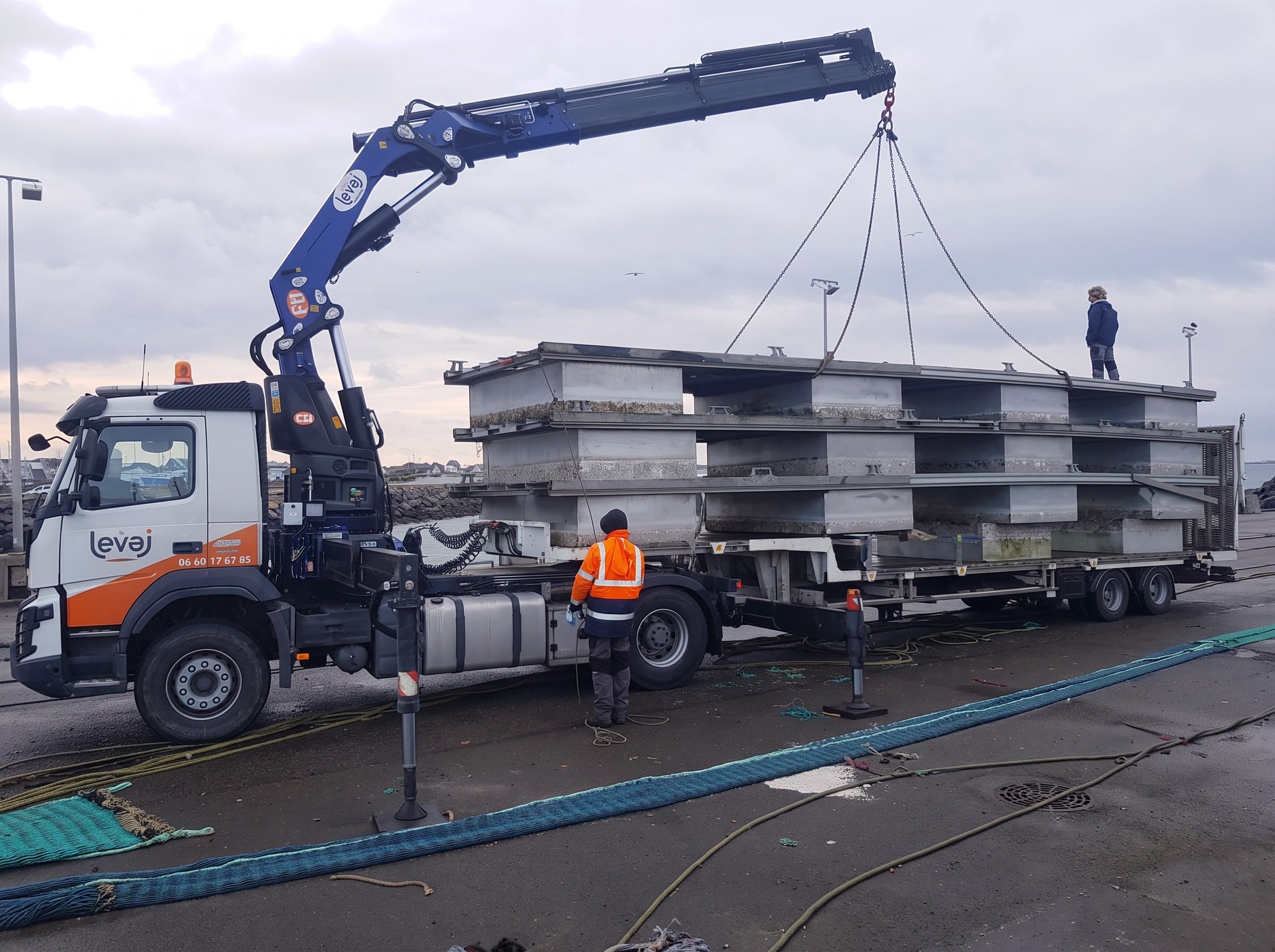 Grue bleue du Volvo FMX levant des structures métalliques sur un quai