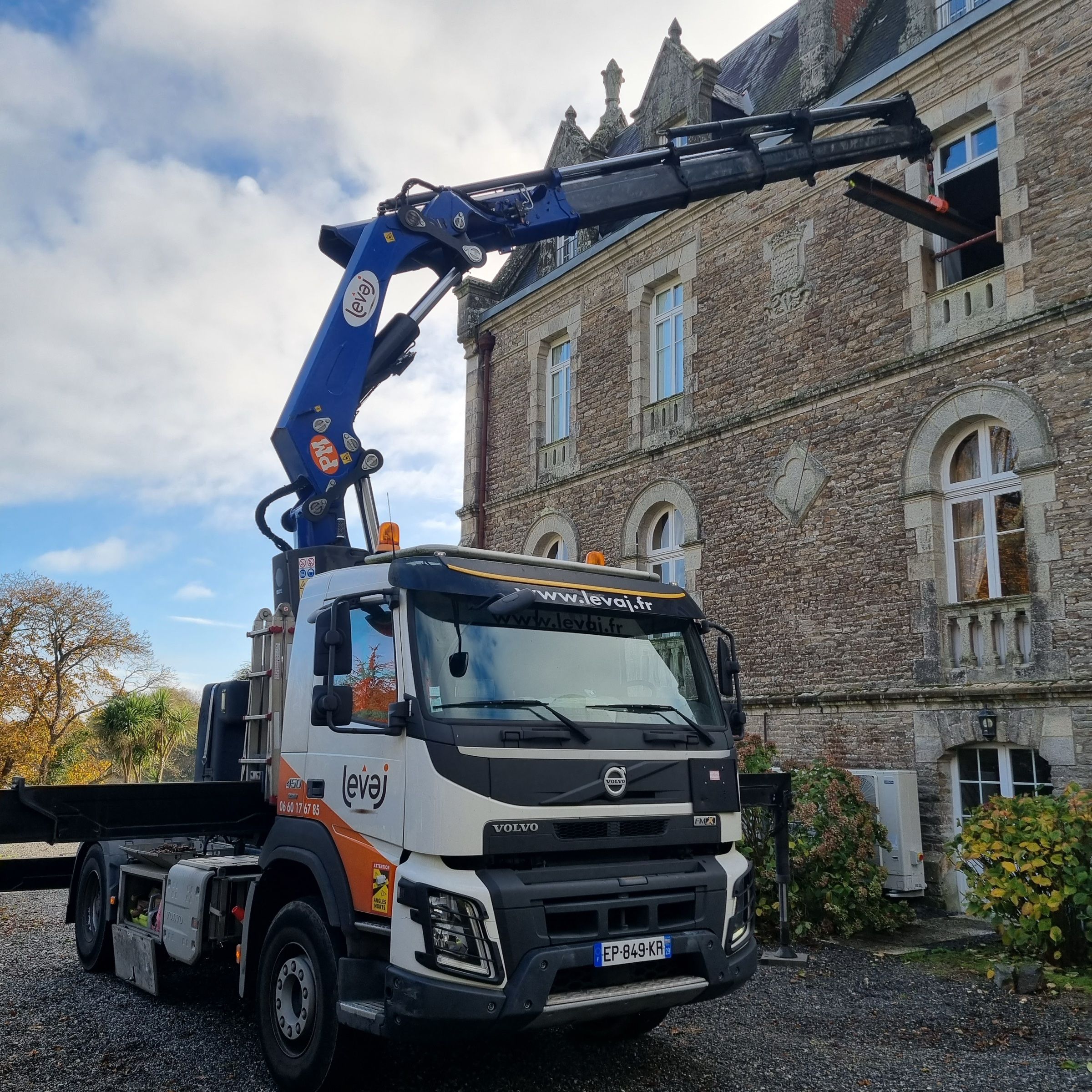 Passage d'une poutre métallique par une fenêtre d'étage d'un château, au Volvo FMX