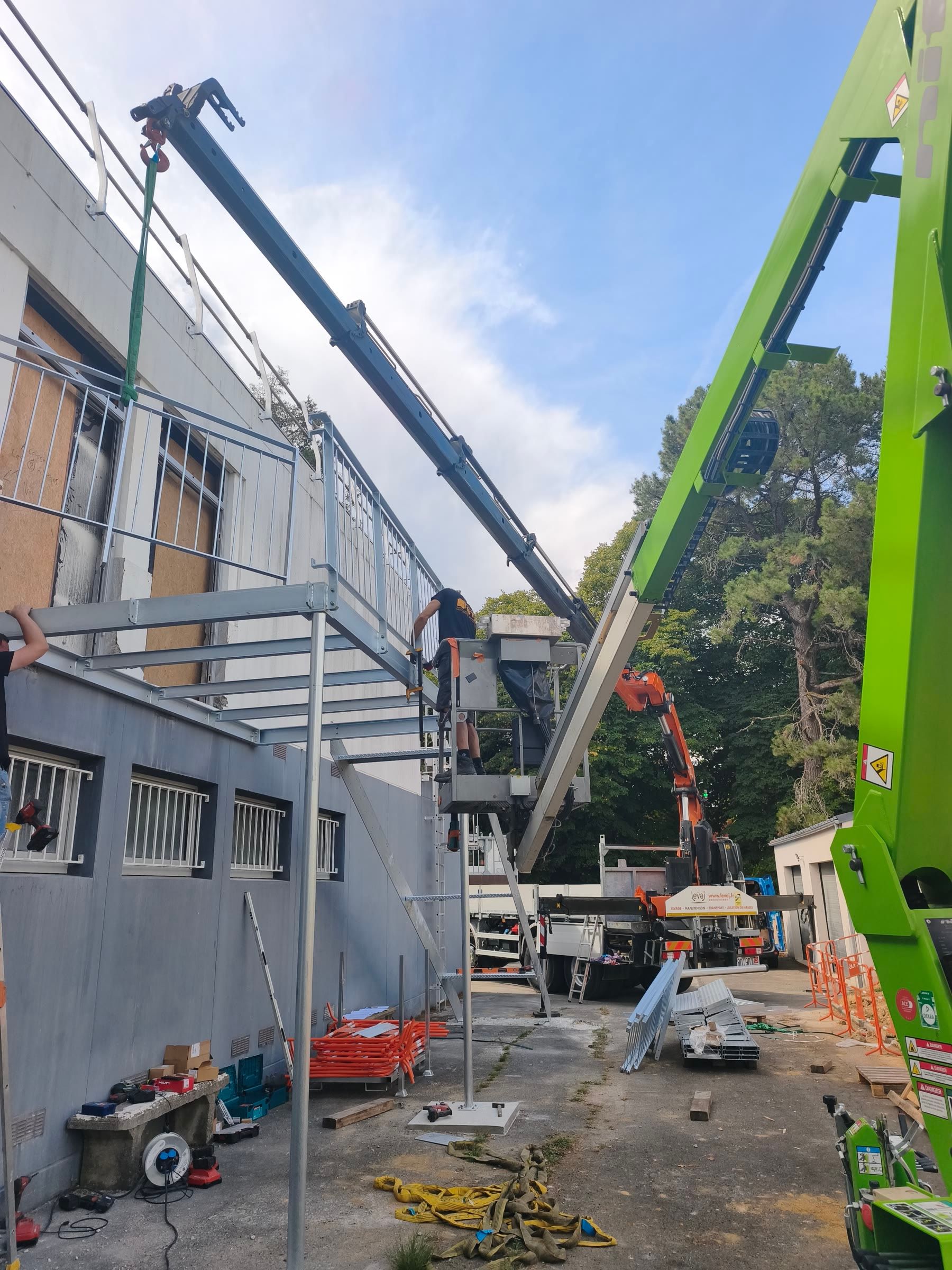 Mise en place d'un escalier métallique contre une façade, au bras de grue